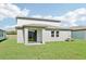Large, grassy backyard featuring a covered patio and sliding glass door at 1740 Brekey Way, Zephyrhills, FL 33541