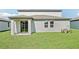 Backyard featuring a covered patio, green grass, and sliding glass doors at 1740 Brekey Way, Zephyrhills, FL 33541
