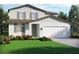Charming two-story home featuring white stucco, sage shutters, manicured lawn, and an attached two-car garage at 1740 Brekey Way, Zephyrhills, FL 33541