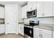 Modern kitchen features stainless steel appliances, granite countertops, and sleek white cabinetry at 1740 Brekey Way, Zephyrhills, FL 33541