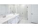 Modern bathroom with double sinks, glass-enclosed shower, white cabinets, and marble-look tile flooring at 1799 Draughton Dr, Zephyrhills, FL 33541