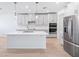 Modern kitchen featuring an island with pendant lighting, stainless steel appliances, light wood flooring, and subway tile backsplash at 1799 Draughton Dr, Zephyrhills, FL 33541