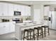 Modern kitchen features white cabinets, stainless steel appliances, an island, and three bar stools at 1859 Draughton Dr, Zephyrhills, FL 33541