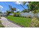 Landscaped backyard with manicured lawn, palm trees and white fence providing a private outdoor oasis at 2110 W Farwell Dr, Tampa, FL 33603
