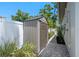 Outdoor storage shed on a paver path with manicured landscaping, next to a white fence at 2110 W Farwell Dr, Tampa, FL 33603