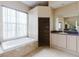 Bathroom with tiled flooring, soaking tub, large window, walk-in shower, and vanity with cabinets at 2707 Wood Pointe Dr, Holiday, FL 34691