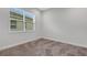 Cozy bedroom featuring plush carpeting, a window, and neutral paint, creating a relaxing atmosphere at 32740 Tree Of Life Ave, Wesley Chapel, FL 33543