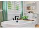 Elegant soaking tub with modern black faucet and green drapes for a luxurious bathing experience at 4754 Manning Ct, Sarasota, FL 34240