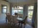 Elegant dining room features a glass table, upholstered chairs, and large windows with curtains at 4875 Hansard Ave, North Port, FL 34286