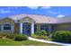 Beautiful one-story home with lush landscaping, arched windows, and charming blue double-door entryway at 4875 Hansard Ave, North Port, FL 34286