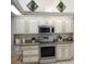 Kitchen featuring white and cream cabinets with granite countertops and stainless steel appliances at 4875 Hansard Ave, North Port, FL 34286