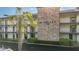 View of the condo building with white balconies and a central stone column with lush landscaping at 6100 12Th S St # 313, St Petersburg, FL 33705
