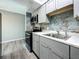 Contemporary kitchen boasts gray cabinetry, stainless steel appliances, and stylish marble backsplash at 6100 12Th S St # 313, St Petersburg, FL 33705