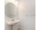Small powder room featuring pedestal sink, round mirror, and neutral paint at 6703 Citrus Creek Ln, Tampa, FL 33625