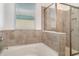 Modern bathtub and glass shower with tiled surround and natural light from window at 7308 Hermes Ct, Apollo Beach, FL 33572