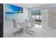 Dining area features a modern glass table, stylish white chairs, and a view of the outdoor pool area at 14506 Sutter Pl, Tampa, FL 33625
