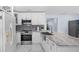 A well-equipped kitchen featuring white cabinets, stainless steel appliances, modern fixtures, and a marble countertop at 14506 Sutter Pl, Tampa, FL 33625