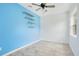 Bright bedroom with unique blue accent wall, modern fan, tile floors, and open shelving for storage and decor at 2706 Flagami Ln, North Port, FL 34286