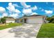A single-story home with a well-manicured lawn and a two-car garage on a sunny day at 2706 Flagami Ln, North Port, FL 34286