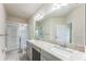 Bathroom featuring double sinks with granite countertops, a large mirror, and a walk-in shower at 8126 Muddy Pines Pl, Tampa, FL 33635