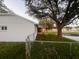 View of the home's backyard, showcasing a small covered porch, chain-link fence, and a mature shade tree at 7342 Skyview Ave, New Port Richey, FL 34653