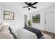 Staged bedroom featuring a ceiling fan, a window with plant, modern artwork and calm design at 9033 3Rd N St, St Petersburg, FL 33702