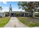 Charming single-story home with a concrete driveway, lush lawn and mature trees at 9033 3Rd N St, St Petersburg, FL 33702
