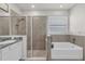 Well-lit bathroom featuring a soaking tub, tiled walk-in shower, and large mirror at 10815 Laxer Cay Loop, San Antonio, FL 33576