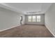 Spacious living room with plush carpet, tray ceiling, and three large windows at 3137 Marine Grass Dr, Wimauma, FL 33598