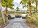 Comfortable outdoor lounge area with cushioned seating, surrounded by lush landscaping and palm trees at 3137 Marine Grass Dr, Wimauma, FL 33598