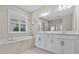 Bright bathroom with a soaking tub, double vanity, and plantation shutters for natural light at 10516 Tranquil Meadow Loop, Riverview, FL 33569
