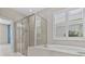 Modern bathroom featuring a glass-enclosed shower, soaking tub, and plantation shutters at 10516 Tranquil Meadow Loop, Riverview, FL 33569