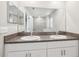Bathroom featuring double sink vanity with granite countertops, mirrors, and a door leading to the shower at 11632 Castine St, New Port Richey, FL 34654