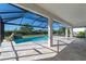 Screened-in pool area featuring a rock waterfall, hot tub, and travertine patio for relaxing at 4861 Antrim Dr, Sarasota, FL 34240