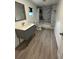 Modern bathroom featuring a sleek vanity, new vinyl flooring, a toilet, and a shower with stylish marble-patterned walls at 8612 N Alaska St, Tampa, FL 33604