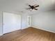 Bedroom with wood-look floors, ceiling fan, closet and entry door with mirror at 7337 Cone Shell Dr, Spring Hill, FL 34607