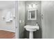 Stylish powder room with a pedestal sink, modern fixtures, and decorative mirror at 2731 Penzance St, Palm Harbor, FL 34684