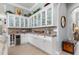 Elegant butler's pantry boasts white cabinetry, brick backsplash, wine storage, and glass display cabinets at 13064 N Marsh Dr, Port Charlotte, FL 33953