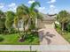 Charming single Gathering home featuring lush landscaping, manicured lawn, and a brick paver driveway at 13064 N Marsh Dr, Port Charlotte, FL 33953