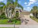 Charming single Gathering home featuring lush landscaping, manicured lawn, and a brick paver driveway at 13064 N Marsh Dr, Port Charlotte, FL 33953