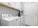 An efficient laundry room features modern washer and dryer, white shelving and cabinets at 13064 N Marsh Dr, Port Charlotte, FL 33953