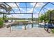 A screened-in pool with a waterfall feature is surrounded by pavers and lush landscaping, offering a relaxing outdoor space at 13064 N Marsh Dr, Port Charlotte, FL 33953