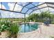 Enclosed pool area with water feature, tropical plants, a flamingo float and a beautiful lake view at 13064 N Marsh Dr, Port Charlotte, FL 33953