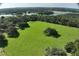 Lush green field with mature trees, bordered by a fence, and a nearby lake at 17380 Sweetwater Rd, Dade City, FL 33523