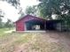 Exterior view of red barn with an open-air garage at 17380 Sweetwater Rd, Dade City, FL 33523