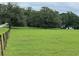 Expansive green field with distant home, bordered by a rustic wooden fence, a picturesque setting at 17380 Sweetwater Rd, Dade City, FL 33523