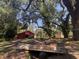 Picturesque home featuring a wooden bridge over a creek, barn and yellow shed on a tree-lined lot at 17380 Sweetwater Rd, Dade City, FL 33523
