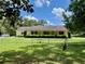 Inviting single-story home with white picket fence, lush lawn, and a decorative antique farm wheel at 17380 Sweetwater Rd, Dade City, FL 33523
