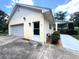 Attached garage with adjacent entrance, framed by manicured shrubbery and mature trees at 17380 Sweetwater Rd, Dade City, FL 33523