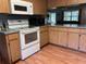 Kitchen with white appliances, wood floors, and wood cabinets at 17380 Sweetwater Rd, Dade City, FL 33523